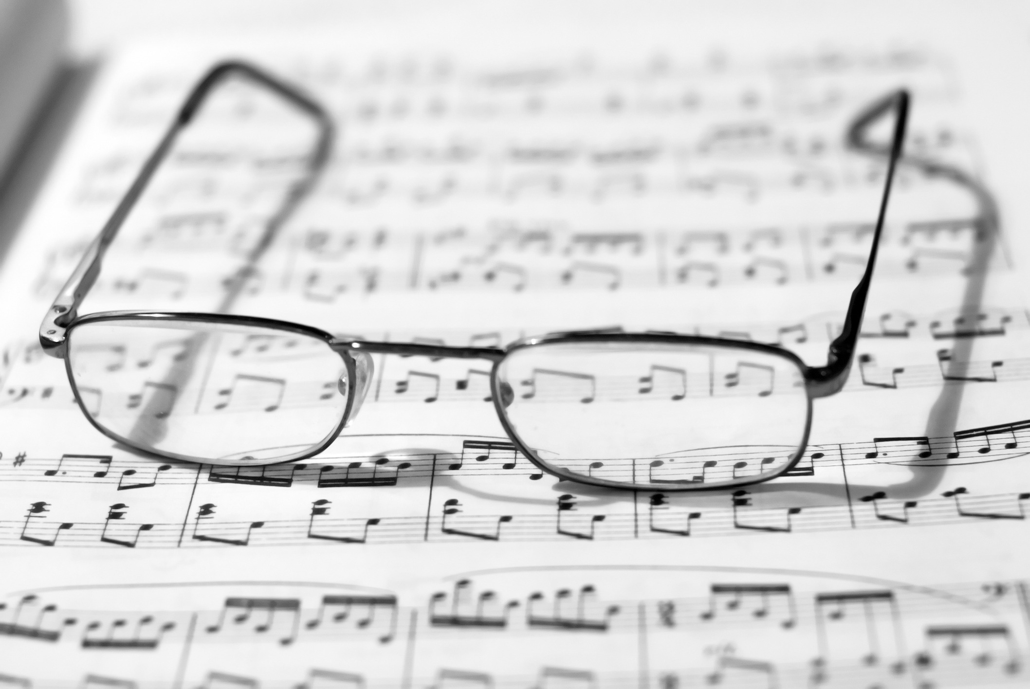 A pair of glasses sitting on top of a musical score