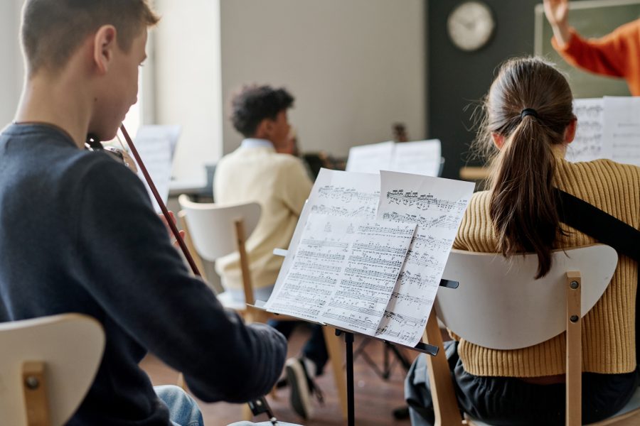 Teenagers playing music and being led by a high school teacher