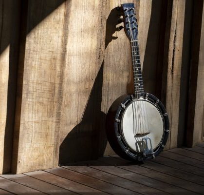 Classic Banjo-mandolin on a porch, sunlight producing dramatic shadows.