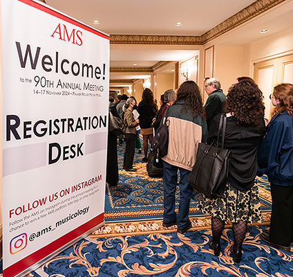 People next to a sign for the AMS registration desk