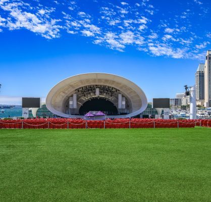 San Diego skyline view with red concert seats, green lawn, and blue sky at Rady Shell